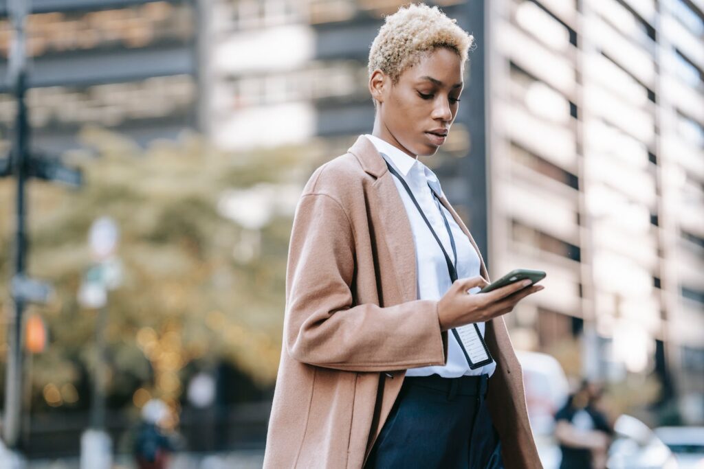 Focused business woman browsing smartphone on urban street